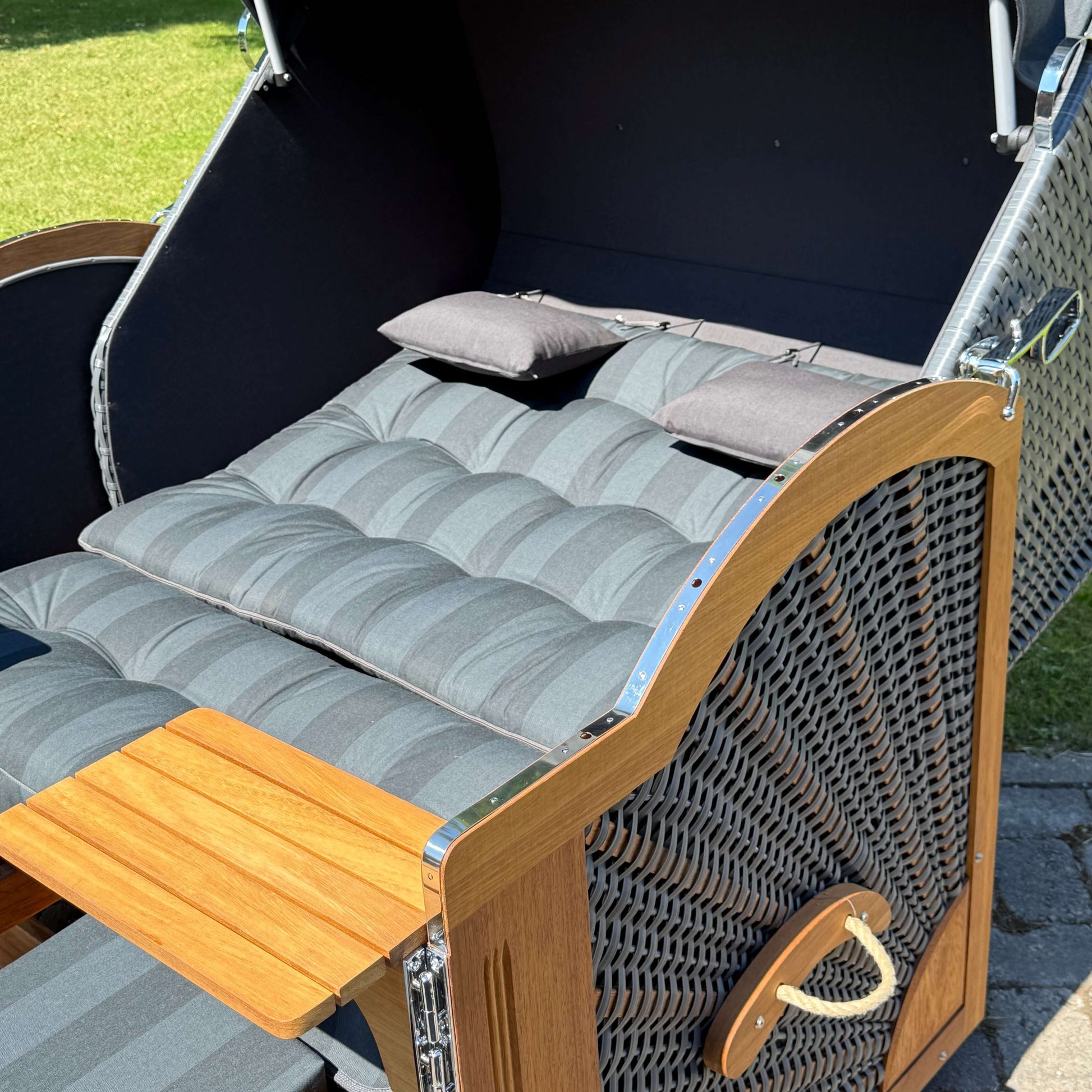 Strandkorb Prieß mit gepolsterten Auflagen, Tisch und dunklem Geflecht, Modell Meister aus Iroko Holz.