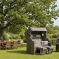 Strandkorb Trendy PURE Wave XL Bullaugen PE grey Dessin 514 anthrazit grau im Garten mit Esstischgruppe und Grill unter großem Baum