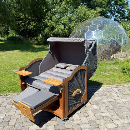 Strandkorb Prieß Modell Meister aus Iroko Holz, dunkelgrauem GEflecht und anthrazitfarbigem Stoff im Freien.