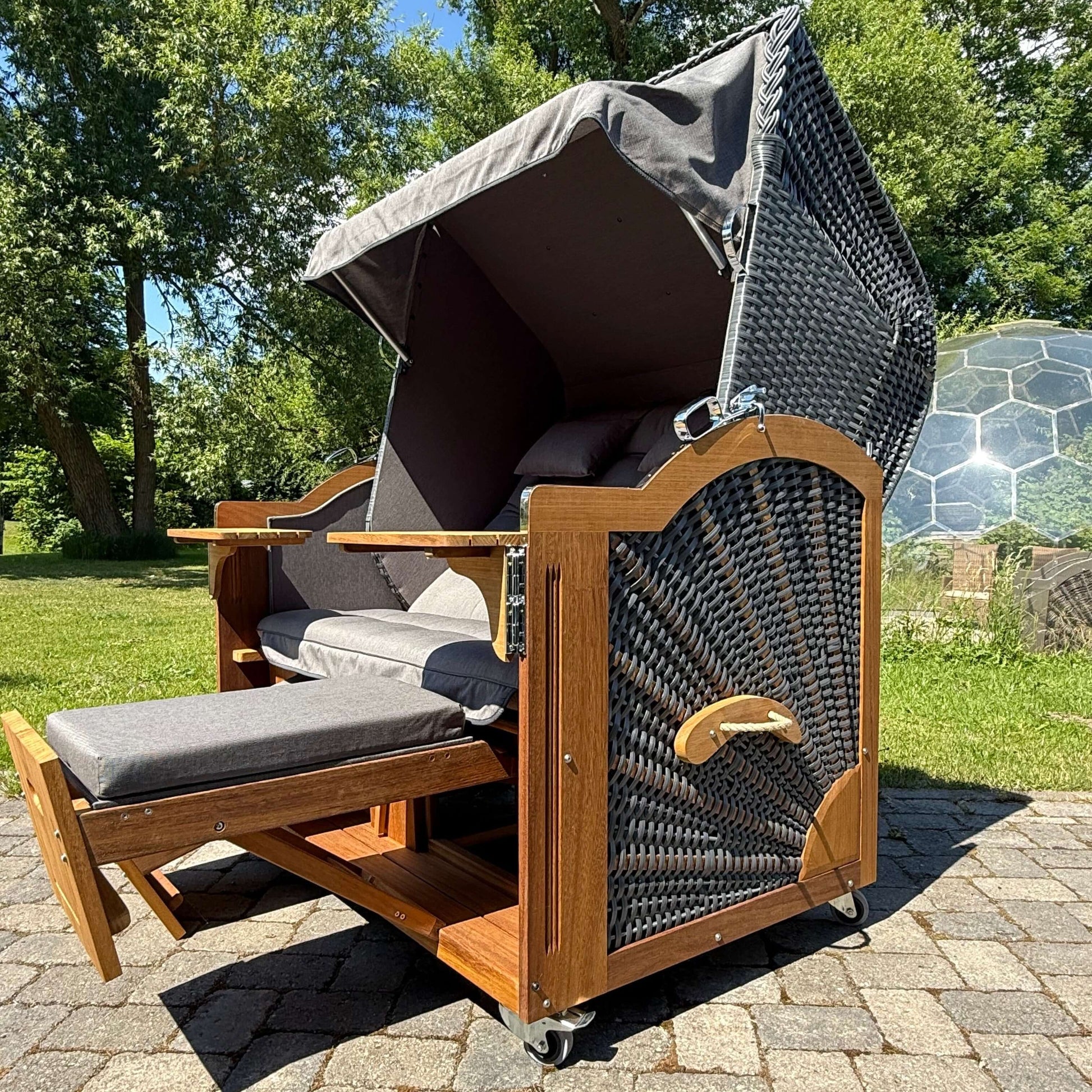 Strandkorb Prieß Modell Meister aus Iroko Holz mit dunkle PE Geflecht und anthrazit grauem Stoff, ideal für den Garten.