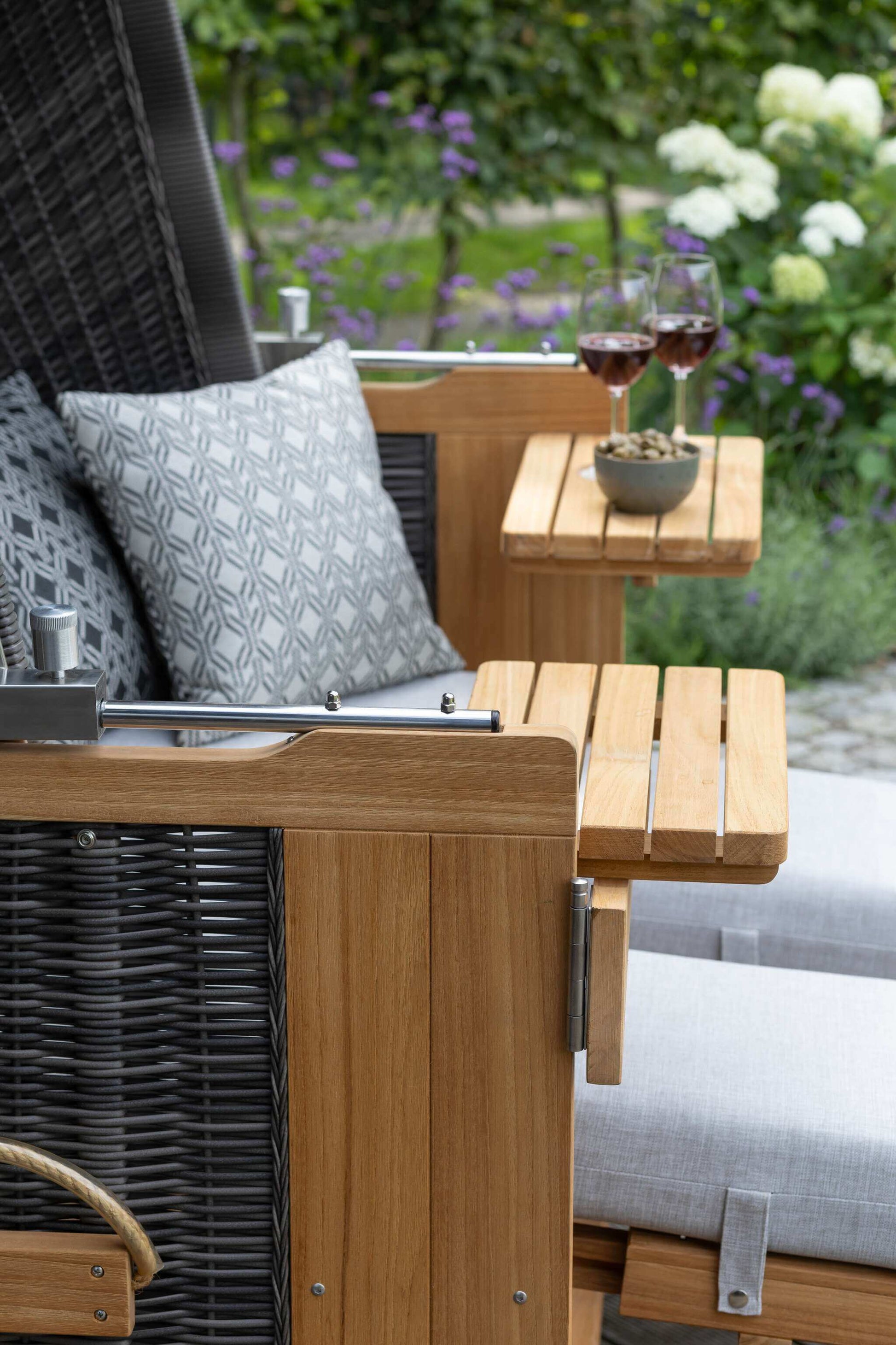 Strandkorb deVries PURE Friesland Sylt Teak PE stone grey Dessin 507 mit Ablagetisch, Polstern und Weingläsern im Garten