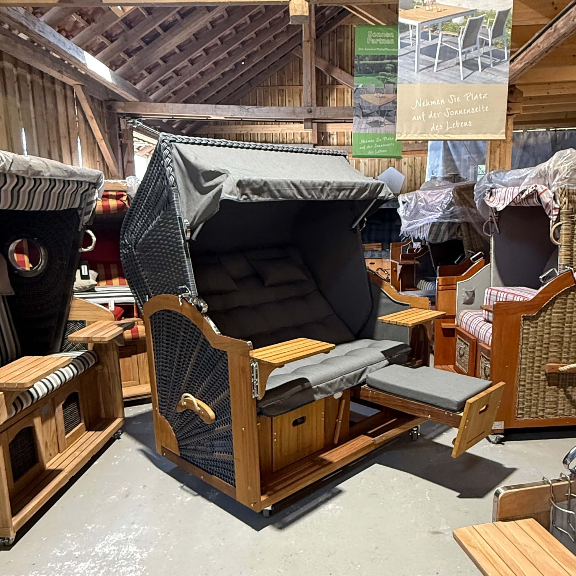 Strandkorb Prieß Modell Meister aus Iroko Holz mit dunkelgrauem PE Geflecht und anthrazit grauem Stoff.