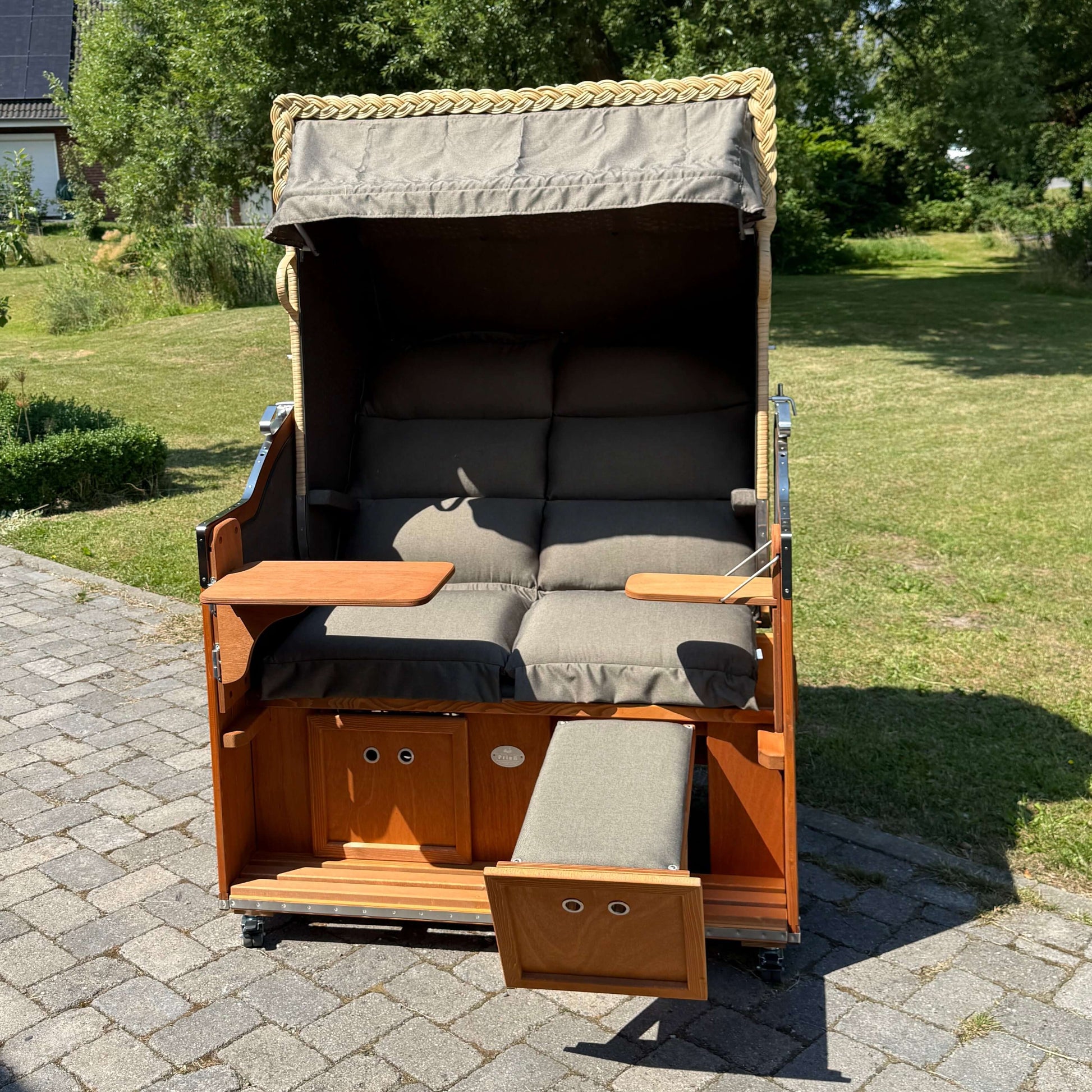 Strandkorb Sonnenpartner Modell Classic PE naturoptik mit gesteppten Polstern und abgedecktem Dach im Garten.