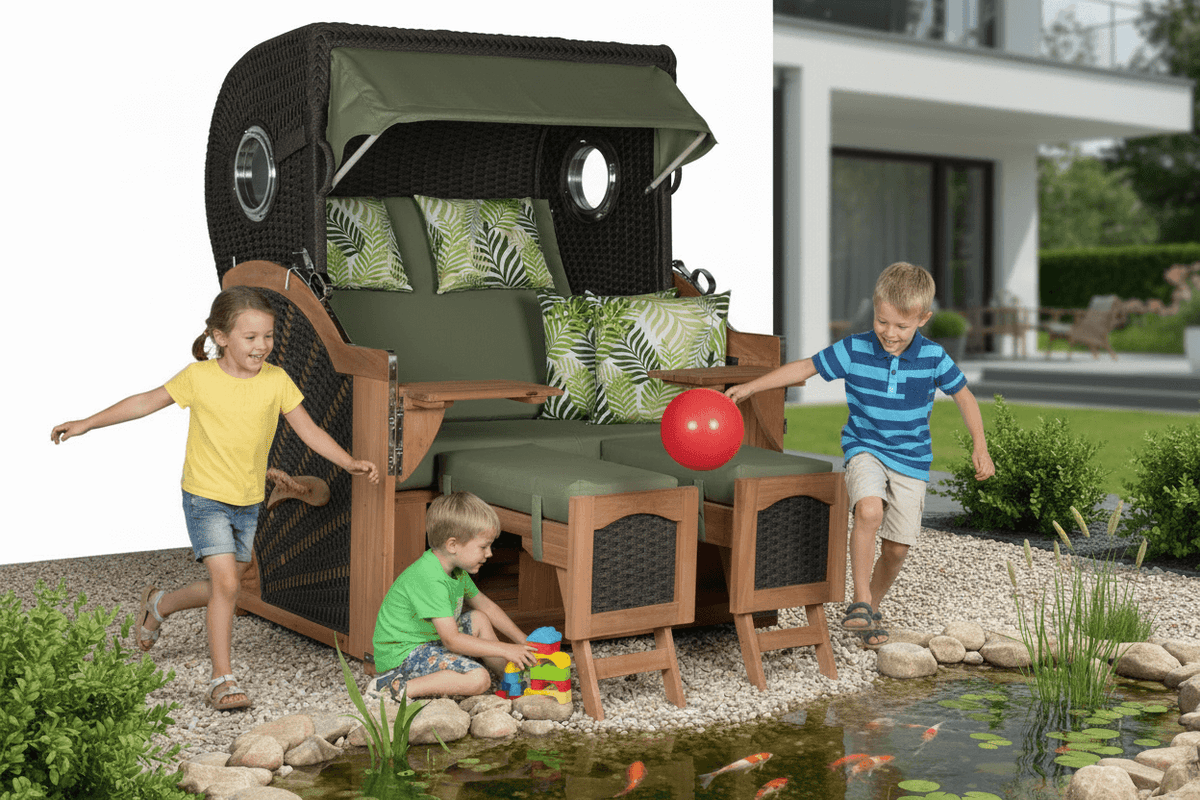 Strandkorb devries Aruba XL Rope anthrazit mit Palmenblatt-Muster grün im Garten, Kinder spielen fröhlich am Teich davor
