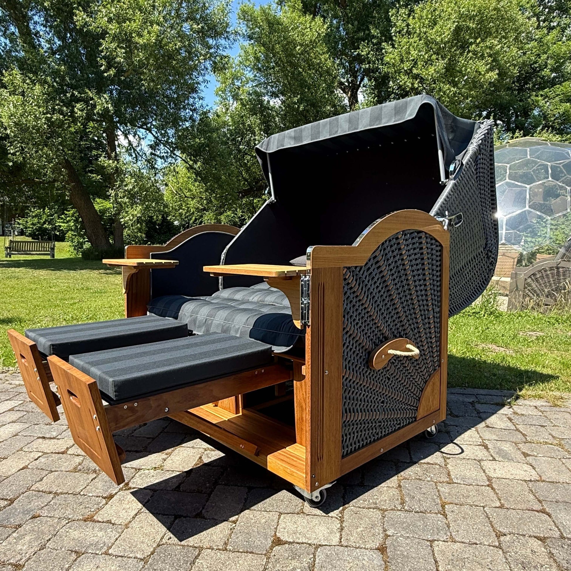Strandkorb Prieß, Modell Meister, Holz Iroko, PE Geflecht dunkelgrau, 150 cm, mit aufklappbarem Dach und Fußstützen.