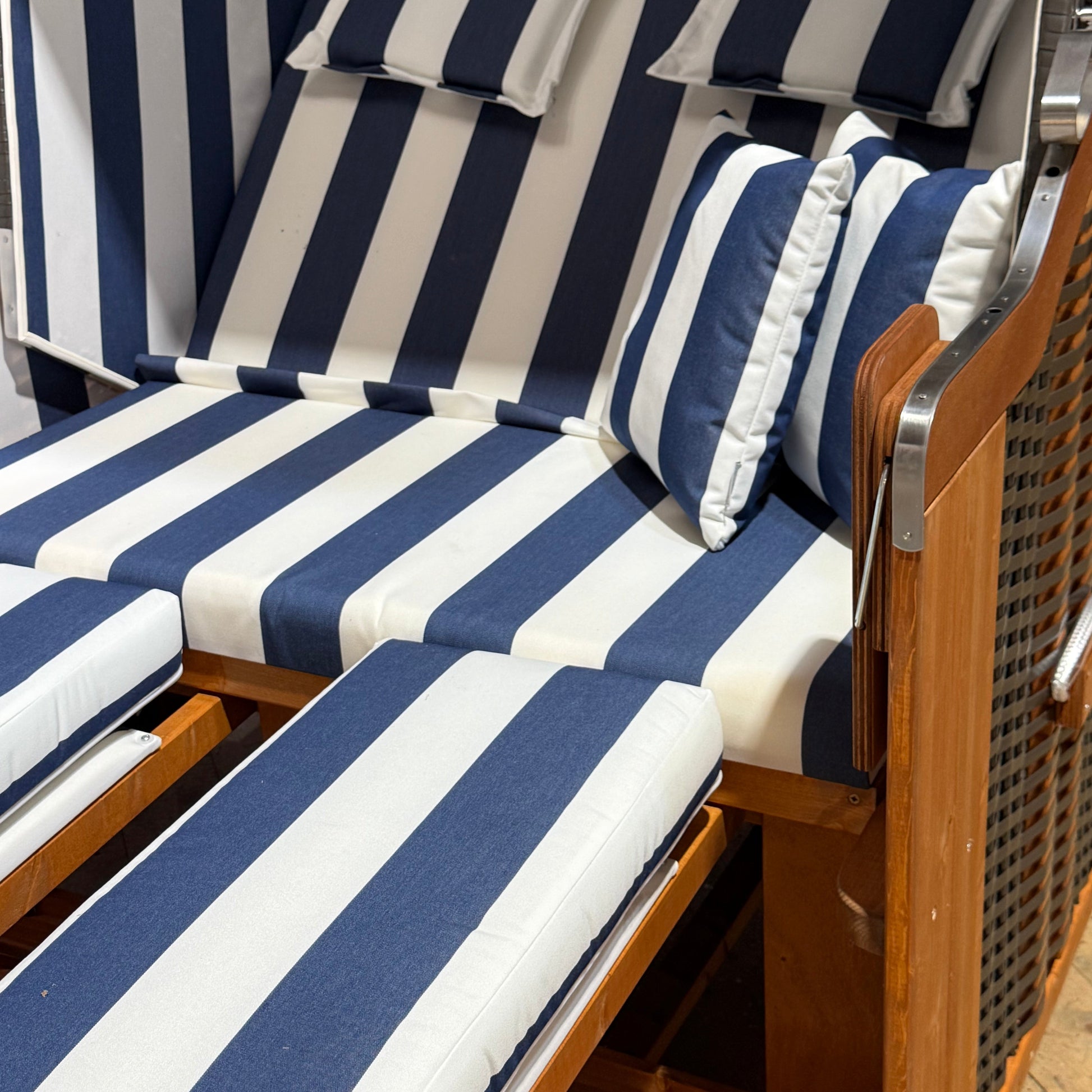 Strandkorb mit blau-weißen gestreiften Polstern und Kopfkissen für entspannende Sommermomente.