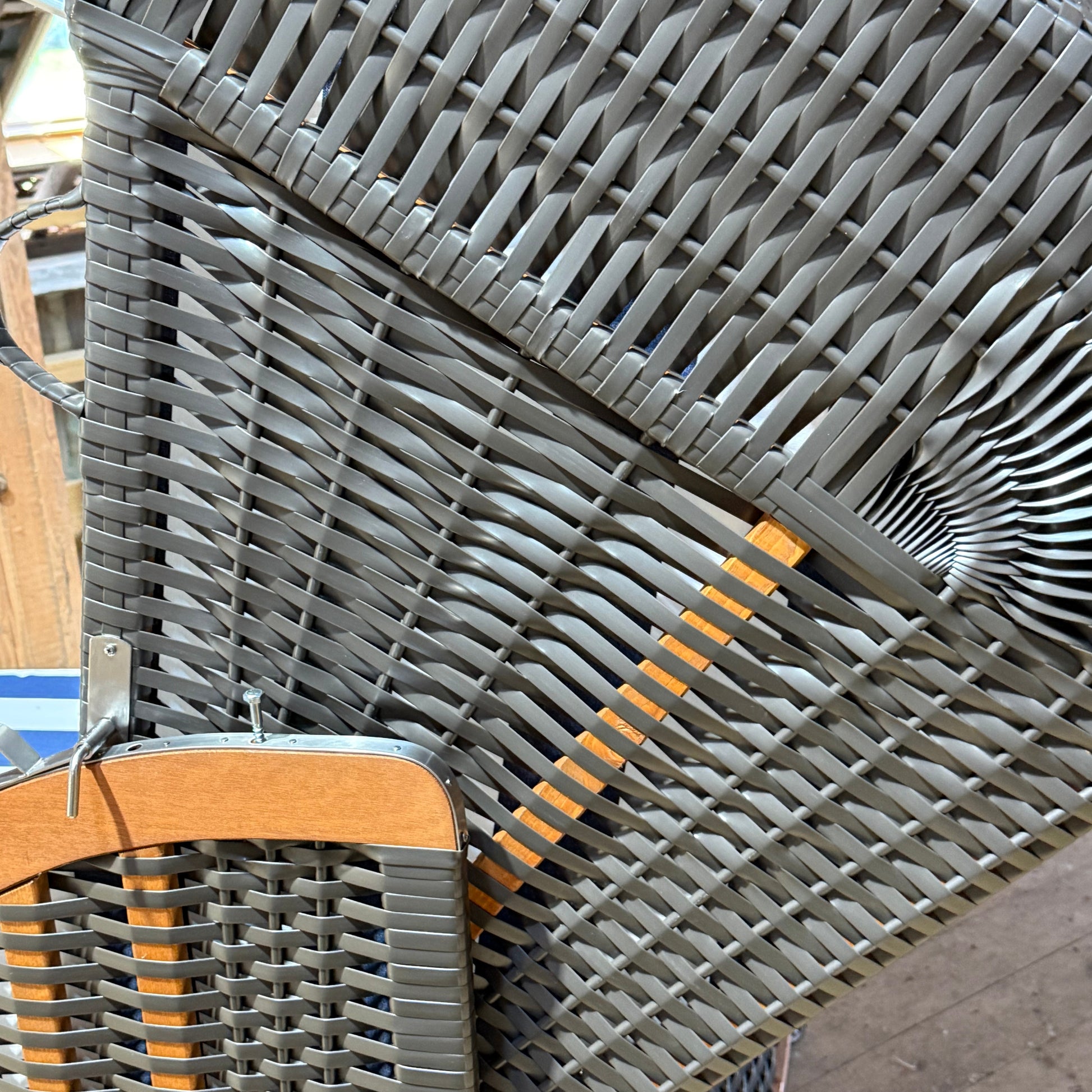 Strandkorb aus anthrazit PVC-Geflecht mit Holzdetails, ideal für das entspannte Sitzen im Freien.
