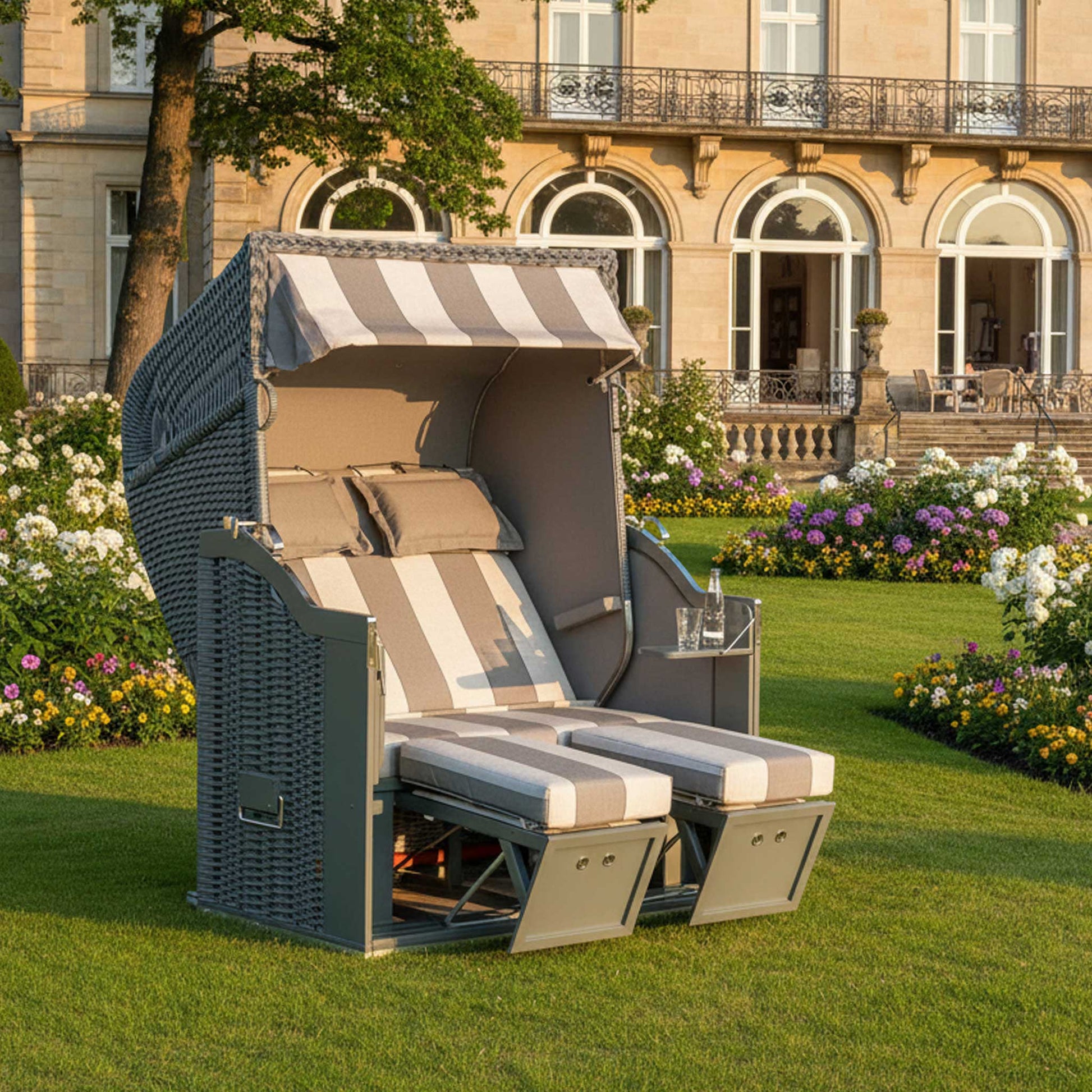 Strandkorb Sonnenpartner Modell Classic PE-Geflecht onix, Holz grau, Dessin 59-727 im Freien mit Blumenbeeten.