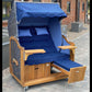 Strandkorb Prieß, Modell Meister, aus Iroko Holz mit dunkelgrauem PE-Geflecht und blau gestreiftem Stoff-Dessin.