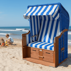 Strandkorb Standard 2-Sitzer aus PVC-Geflecht in dunkelblau mit blau-weißen Streifen am Sandstrand vor dem Meer