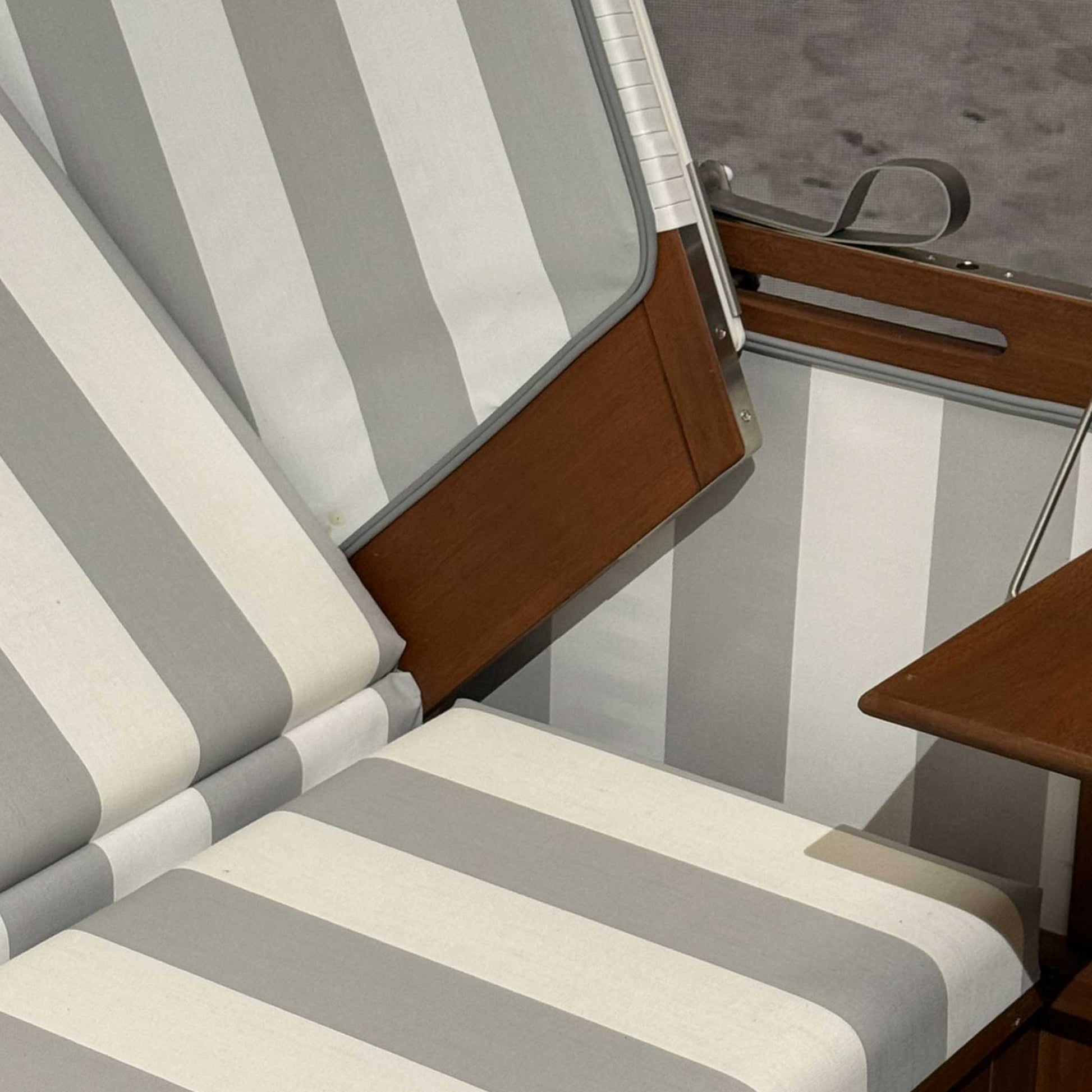 Strandkorb deVries Profi Nordsee Sylt Detail mit grau-weiss gestreifter Polsterung und Mahagoniholz-Seitenteil