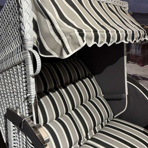 Strandkorb Sonnenpartner Modell Classic PE-Geflecht, grau lasiert, mit gestreiften Kissen in grau schwarz.