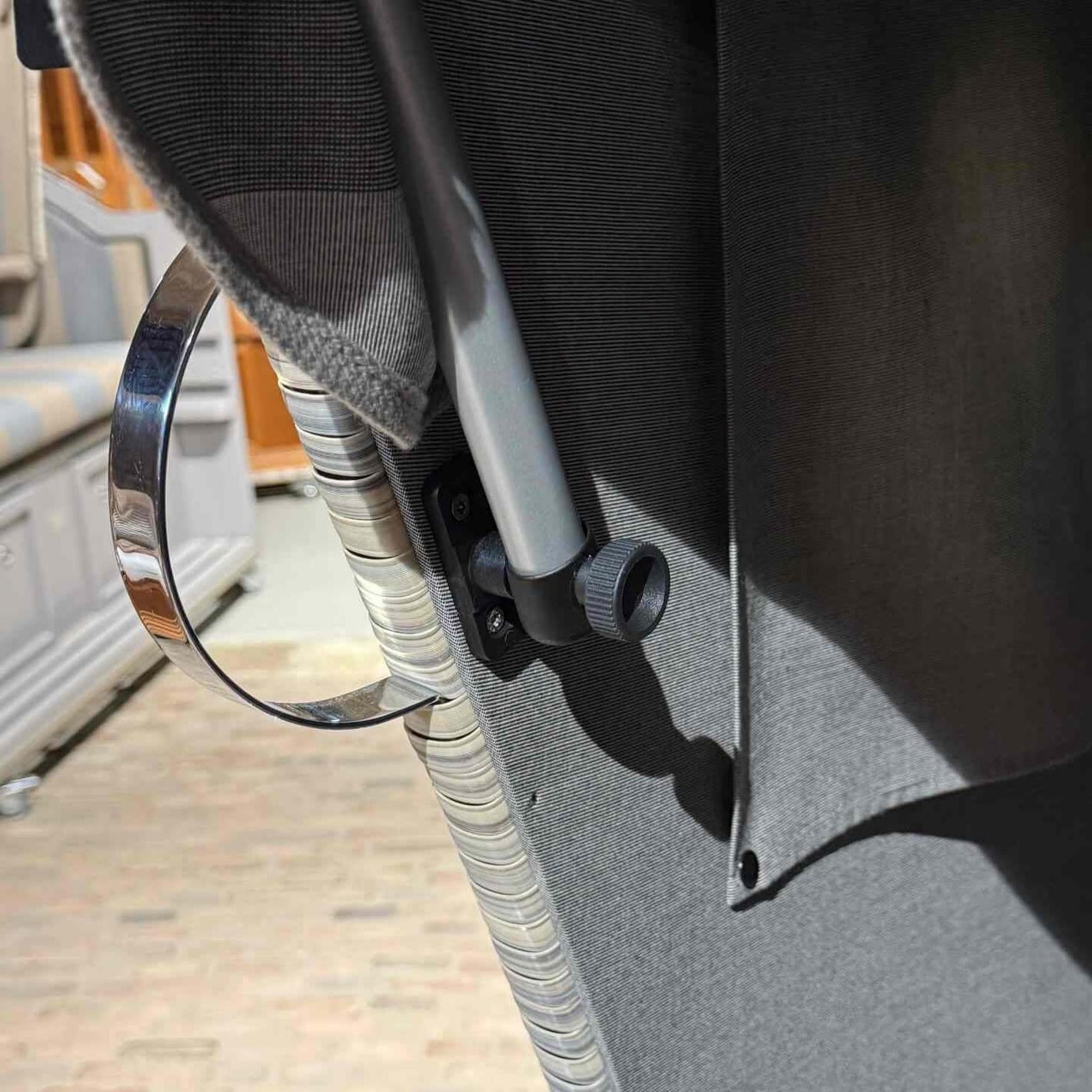 Halter für Sonnenmarkise mit Rändelschraube in der Nähe des Strandkorbs, zeigt Rändelrad und Montage.