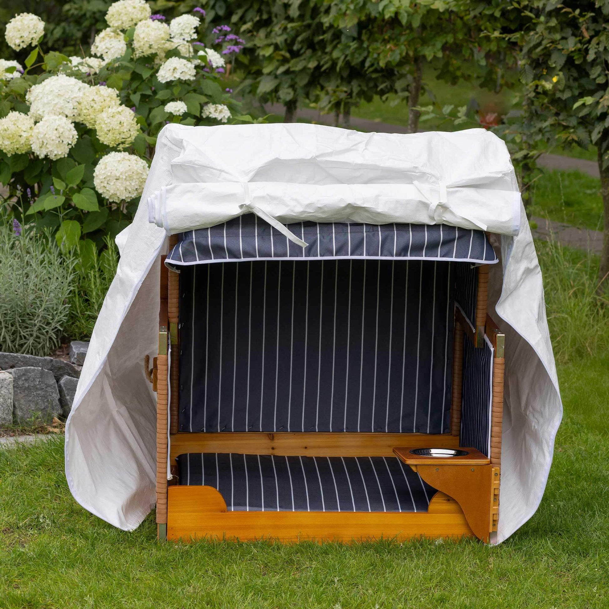 Hundestrandkorb PE natur gestreift rot im Garten unter einem weißen Schutzdach, mit blauen Streifen und natürlicher Holzoptik.