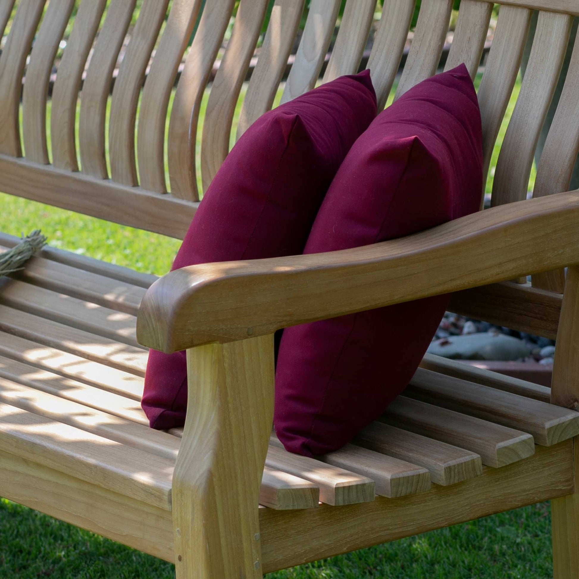 Park Bank Teak aus hochwertigem Teakholz mit zwei roten Kissen auf der Sitzfläche im Garten