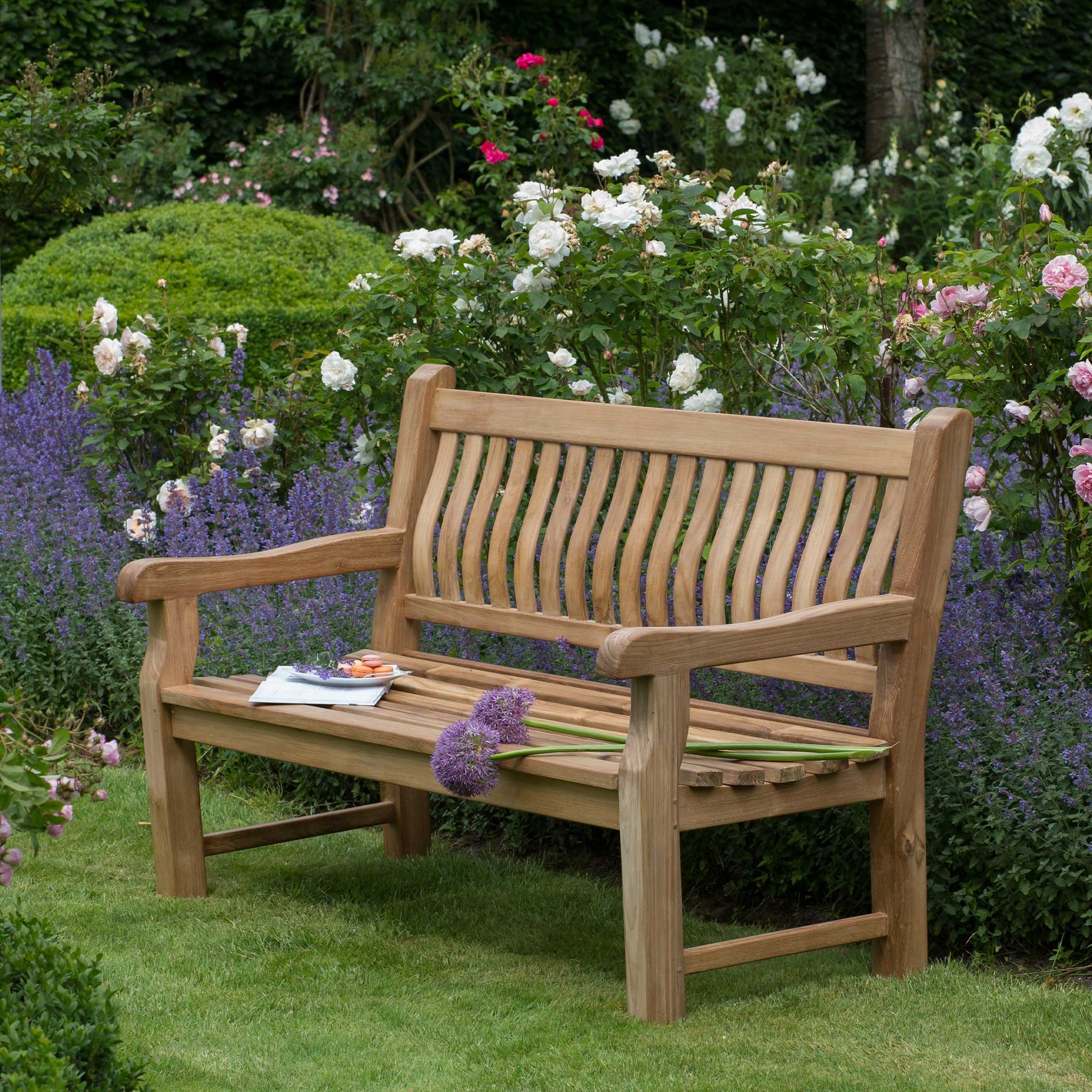 Park Bank Teak aus hochwertigem Teakholz im blühenden Garten, stabile Premium Bank für Terrasse und Outdoor Entspannung