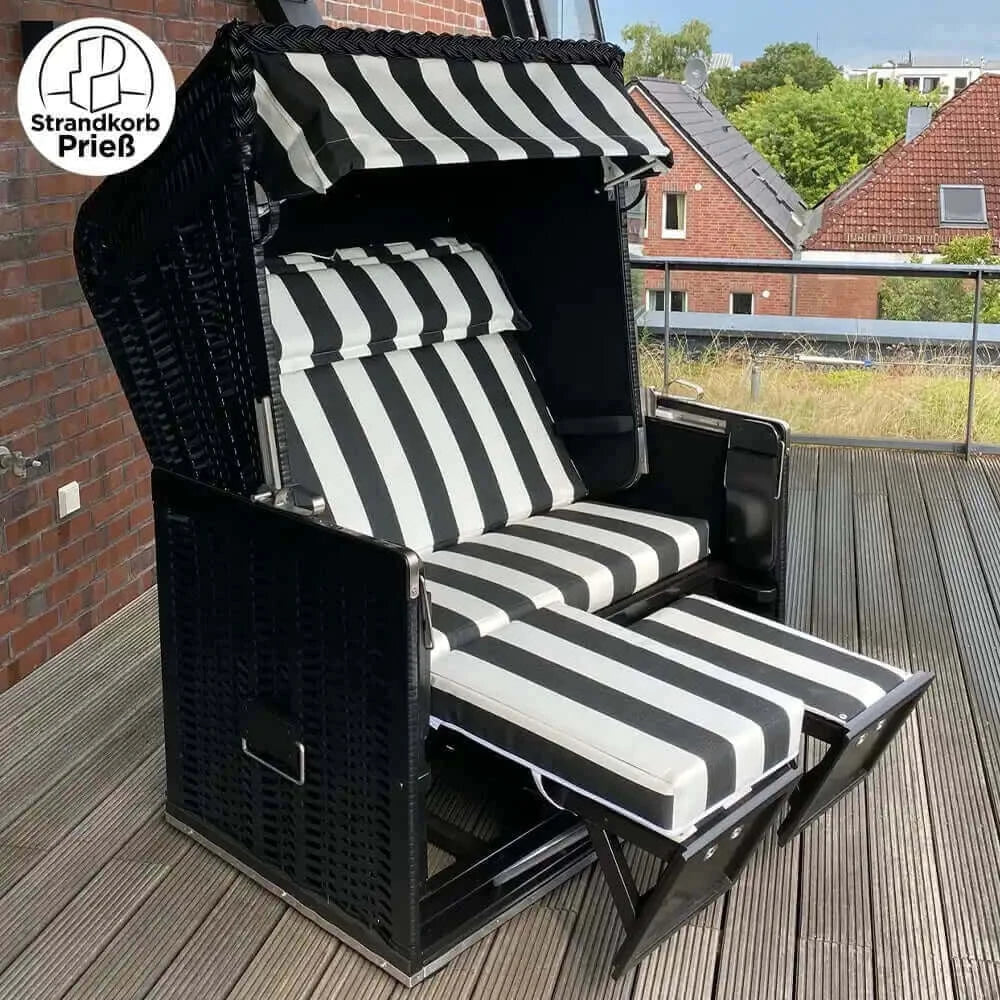 Strandkorb Sonnenpartner Modell Konsul schwarz mit schwarz-weiß gestreiften Polstern und ausziehbaren Fußstützen auf Terrasse