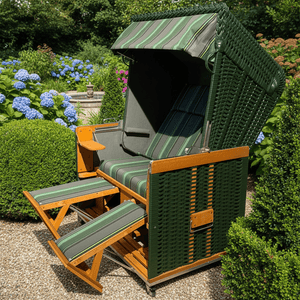 Strandkorb Sonnenpartner Modell Konsul grün mit Fußrasten im Garten, ideal für entspannte Stunden im Freien.
