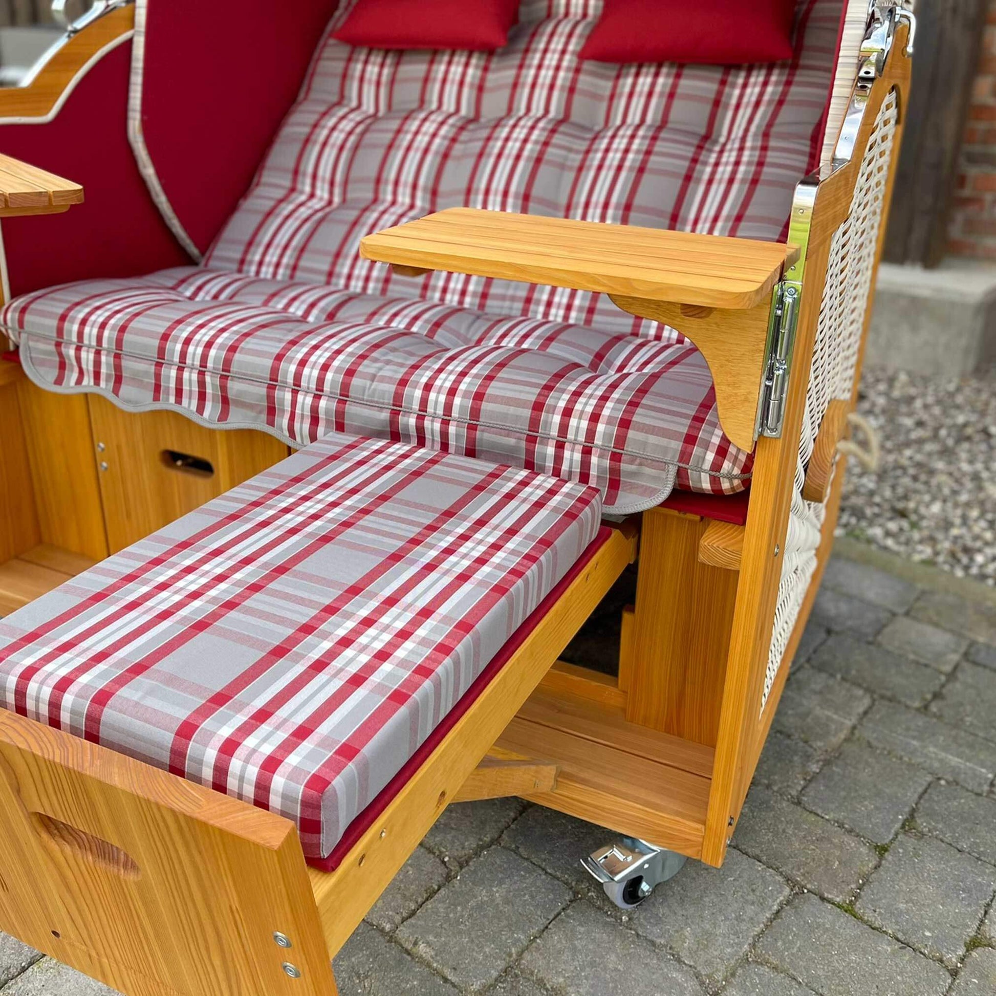 Strandkorb Prieß rot mit gestreiften Kissen und Holzelementen, ideal für Garten oder Terrasse.