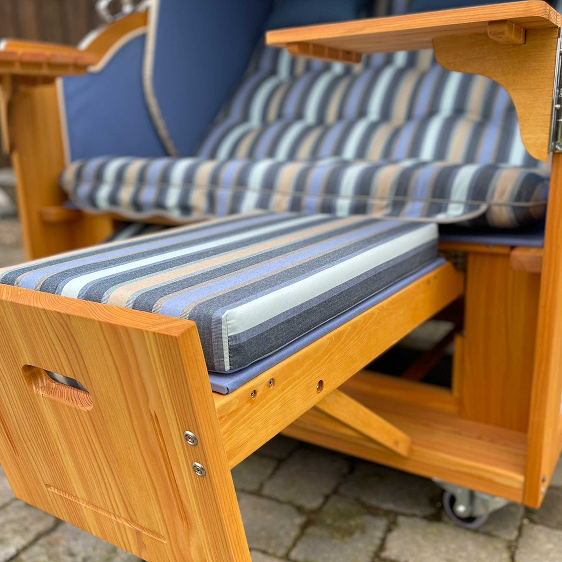 Innenansicht des Strandkorb Prieß Modell Meister mit gestreiften Kissen und Holzrahmen aus Lärche.