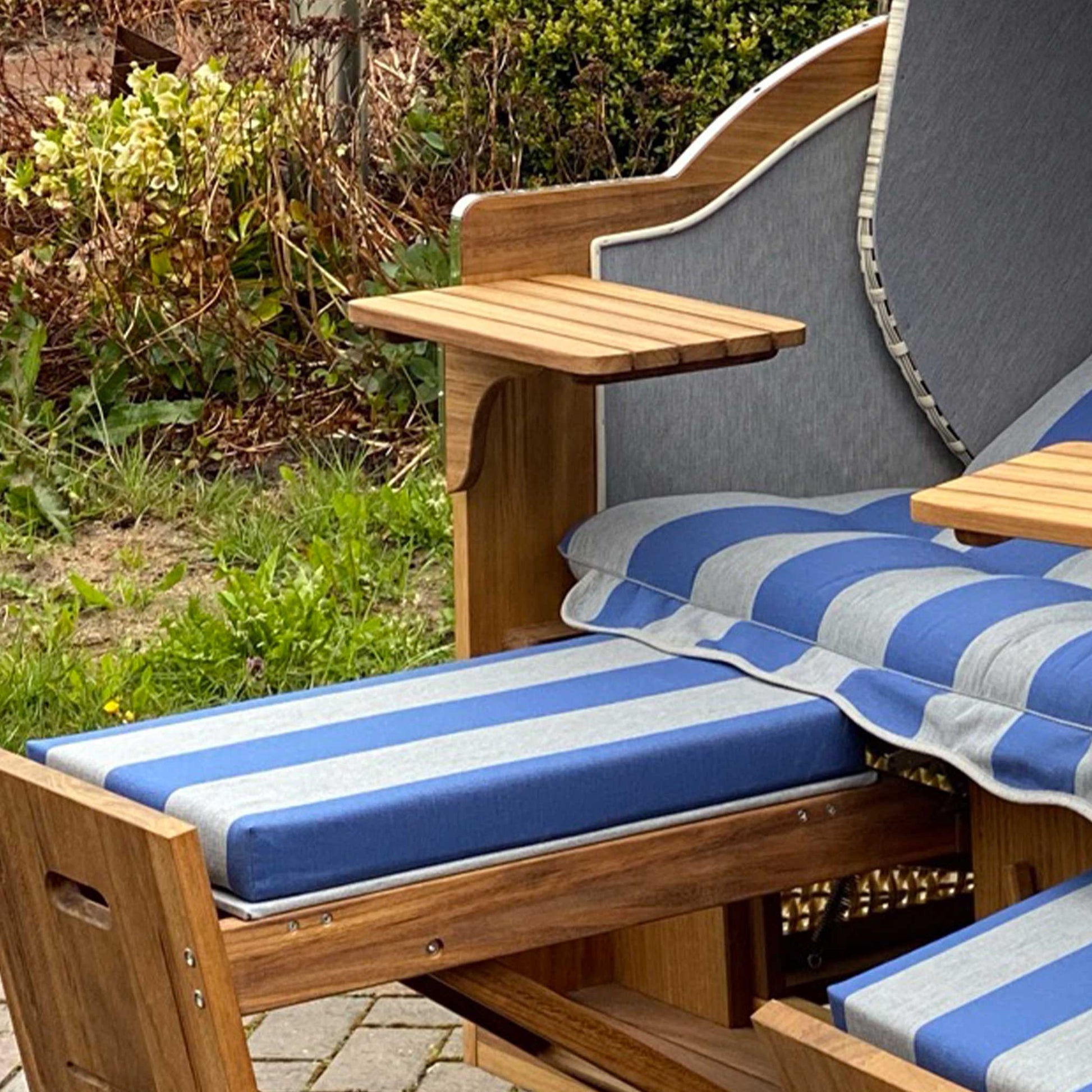 Detailaufnahme vom Strandkorb Prieß, Modell Meister mit blau-gestreiften Kissen und Holzablage.