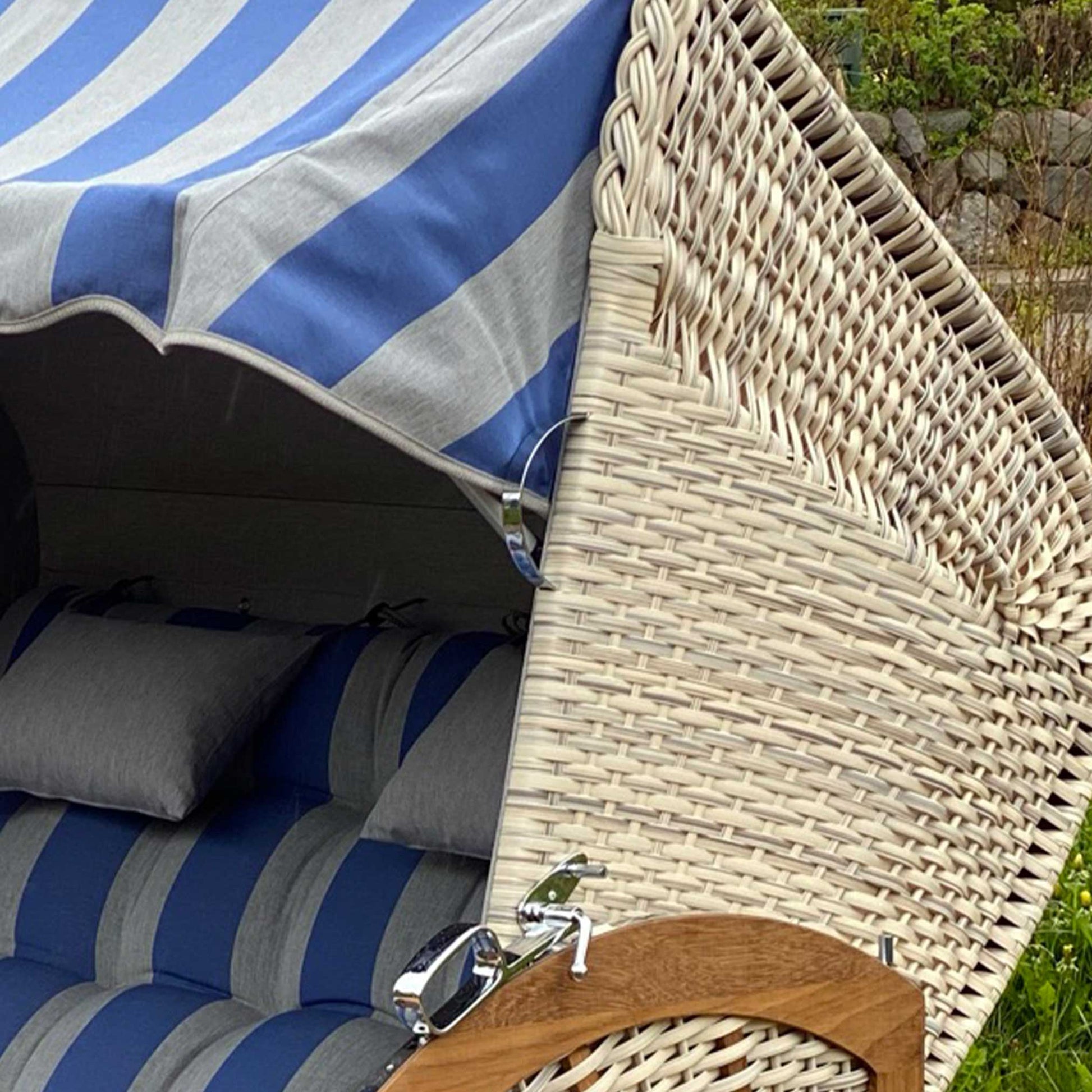 Strandkorb Prieß, Modell Meister mit blau-weiß gestreiftem Dach und Kissen, Iroko Holz und taupe PE-Geflecht.