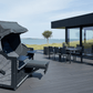 Strandkorb Prieß Modell Meister aus Lärche schwarz, PE Geflecht dunkelgrau auf moderner Terrasse mit Meerblick