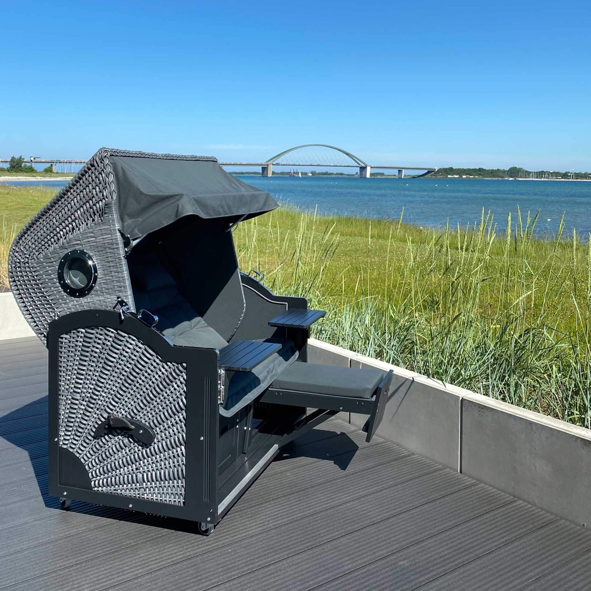 7028 Strandkorb Prieß Modell Meister, Strandkorb schwarz aus Lärche mit dunkelgrauem PE-Geflecht auf Terrasse mit Meerblick