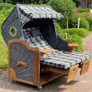 Strandkorb Prieß Modell Meister aus Iroko Holz mit dunkelgrauem PE Geflecht und karierten Polstern im Garten