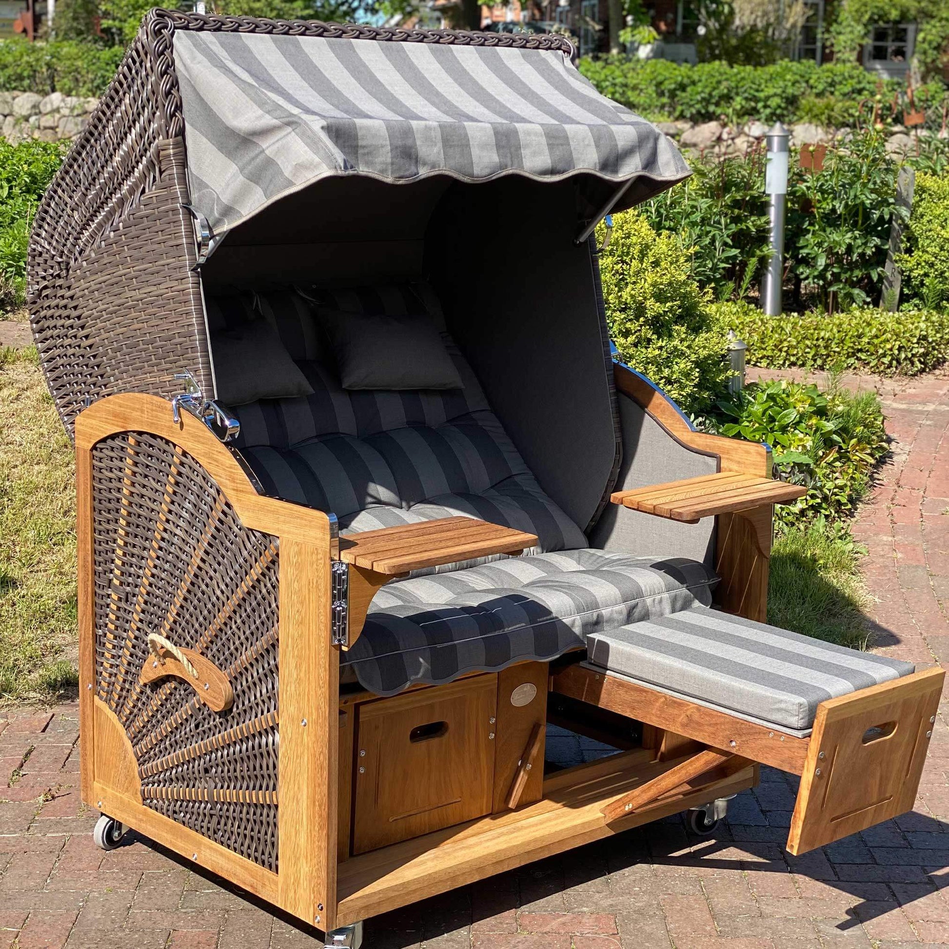 Strandkorb Prieß, Modell Meister, aus Iroko Holz, PE Geflecht in cappuccino, mit anthrazit braunem Stoffdessin und umklappbarem Fußteil.