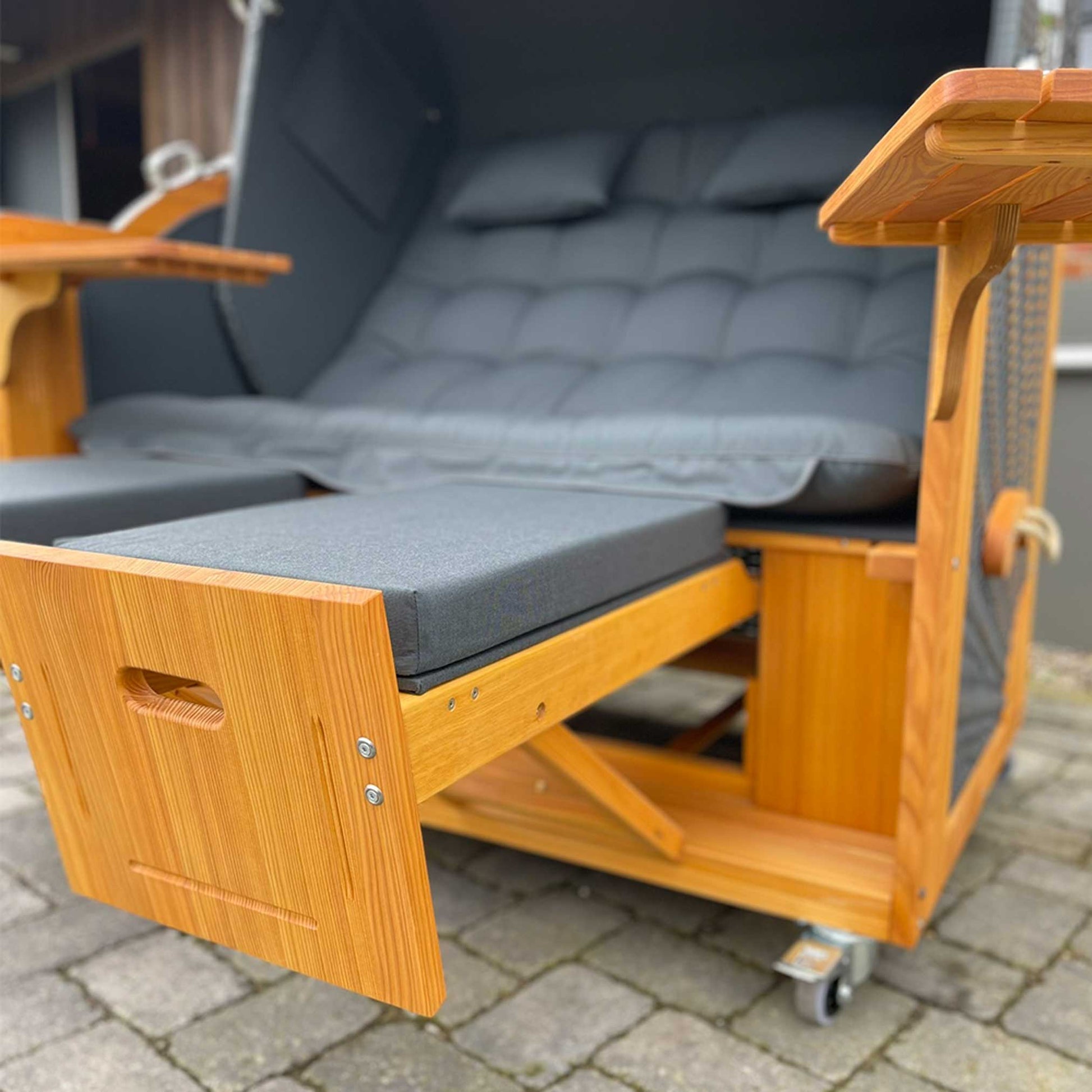 Detailaufnahme des Strandkorb Prieß, Modell Meister mit schwarz gepolstertem Sitz und Lärchenholz-Elementen.