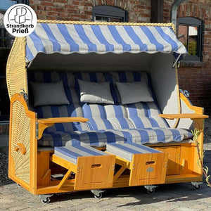 Strandkorb Prieß Meister Lärche Holz mit blau-gestreiftem Stoffdessin, zwei Fußstützen und bequemem Polster.