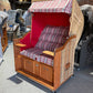 Strandkorb Sonnenpartner Modell Classic mit rot-gestreiftem Polster und Holzgestell, geeignet für 2 Personen.