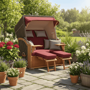 Komplettpaket Strandkorb Seeblick Teak PE grau mit rot bordeaux Polstern in einem blühenden Garten.