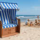 Strandkorb 2-Sitzer blau weiss am Sandstrand vor dem Meer, idealer Strandkorb für Familienurlaub und Sonnenschutz am Wasser