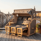 Strandkorb Düne Grande XXL Dreisitzer aus Teak in Grau mit Bullaugen und Fußstützen auf Dachterrasse mit Stadtblick