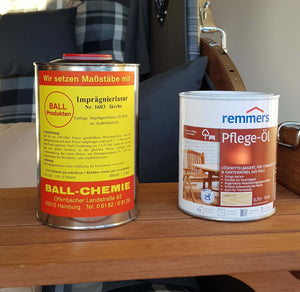 Strandkorb Prieß Pflege-Öl und Lasur für Lärche oder Iroko auf einem Tisch im Hintergrund von einem Strandkorb