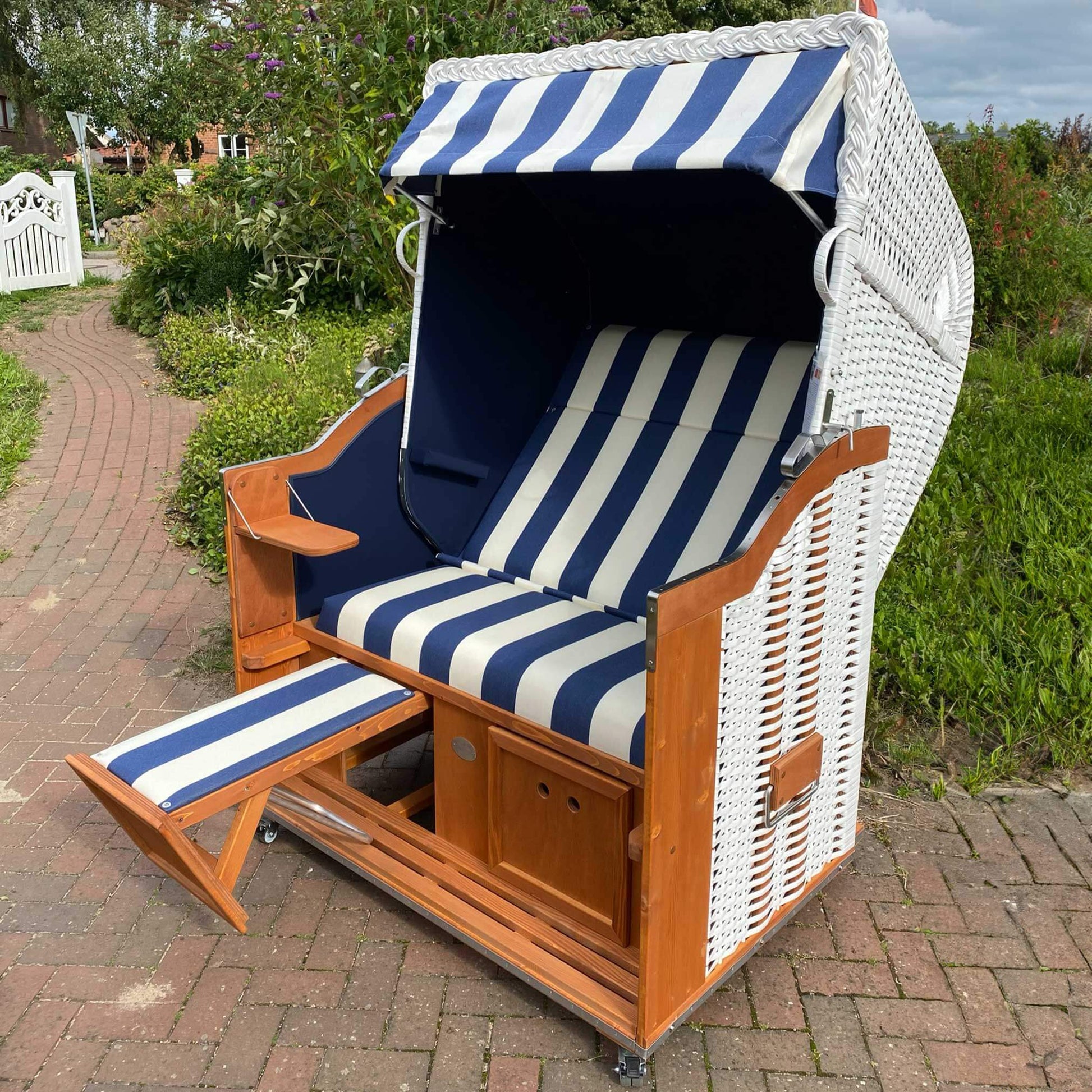 Strandkorb Sonnenpartner Classic weißes Geflecht mit blau weißem Dessin 40, Holz lasiert, Fahrrollen und verstellbarer Fußstütze im Garten