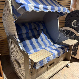 Strandkorb Prieß Modell Meister A120 Vintage grau mit blau-gestreifter Polsterung und ausklappbaren Tischen im Innenbereich