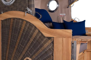 Strandkorb Baltikum Bullauge Teak PE Grey XL mit blauen Kissen und Holzdetails für den Garten.