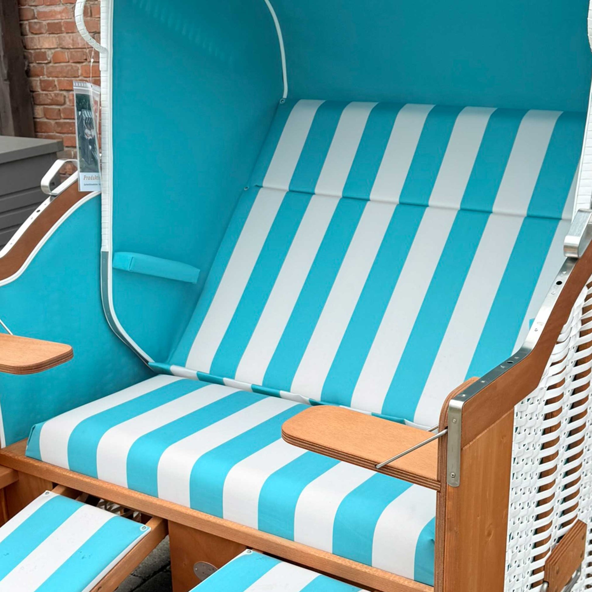 Strandkorb Sonnenpartner Modell Classic PVC weiß, Holz lasiert, türkis weiß gestreifte Polsterung auf bequemer Sitzgelegenheit.