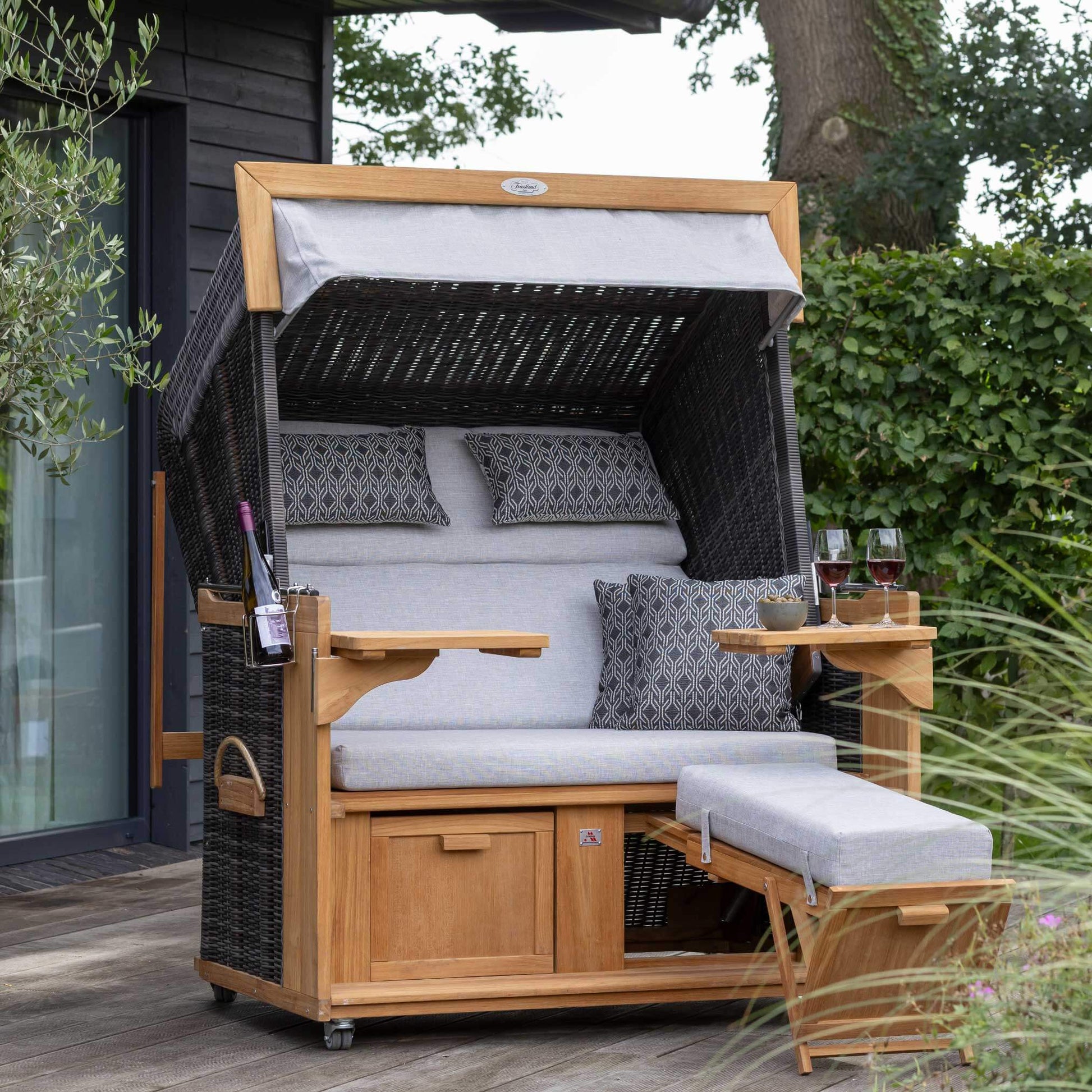 Strandkorb deVries PURE Friesland Sylt Teak PE stone grey Dessin 507 XL auf Terrasse mit Fußstütze, Kissen und Ablagetischen