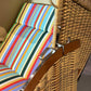 Strandkorb Sonnenpartner Modell Classic PE Naturoptik mit buntem Streifenmuster und lasierter Holzarmlehne.