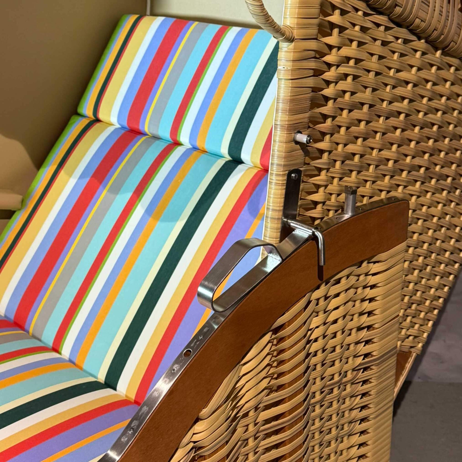 Strandkorb Sonnenpartner Modell Classic PE Naturoptik mit buntem Streifenmuster und lasierter Holzarmlehne.