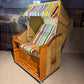 Strandkorb Sonnenpartner Modell Classic PE Naturoptik mit buntem Streifenmuster und Holzlasur, ideal für Entspannung im Freien.