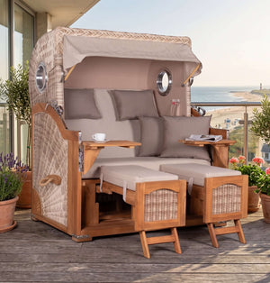 Strandkorb Prieß - Fachhandel Düne Grande 2,5-Sitzer aus Teakholz mit Bullaugen, creme gestreiftem Bezug und Fußstützen.