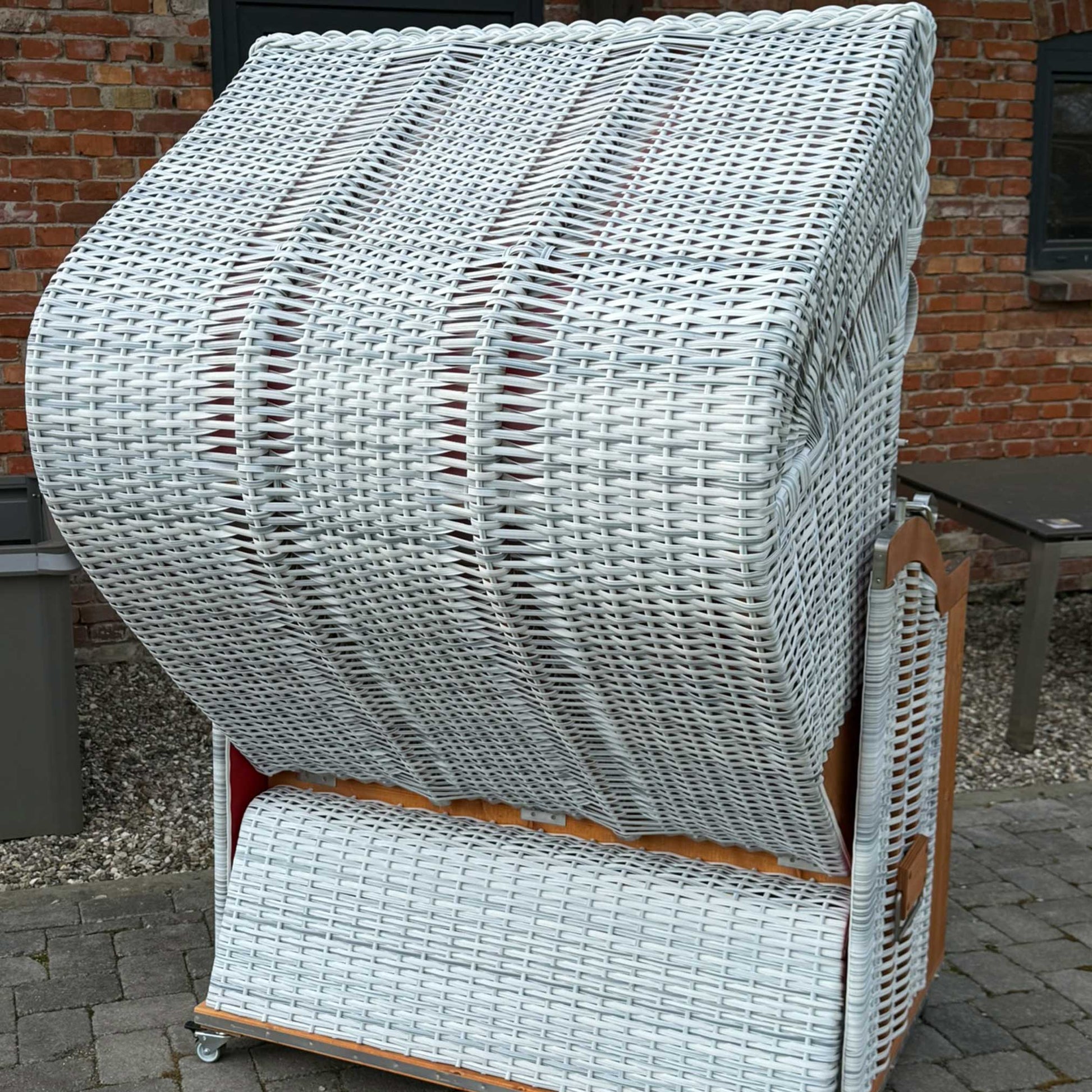 Strandkorb Sonnenpartner Modell Classic in weiß gewaschenem Holz mit buntem Dessin rot und weiß.