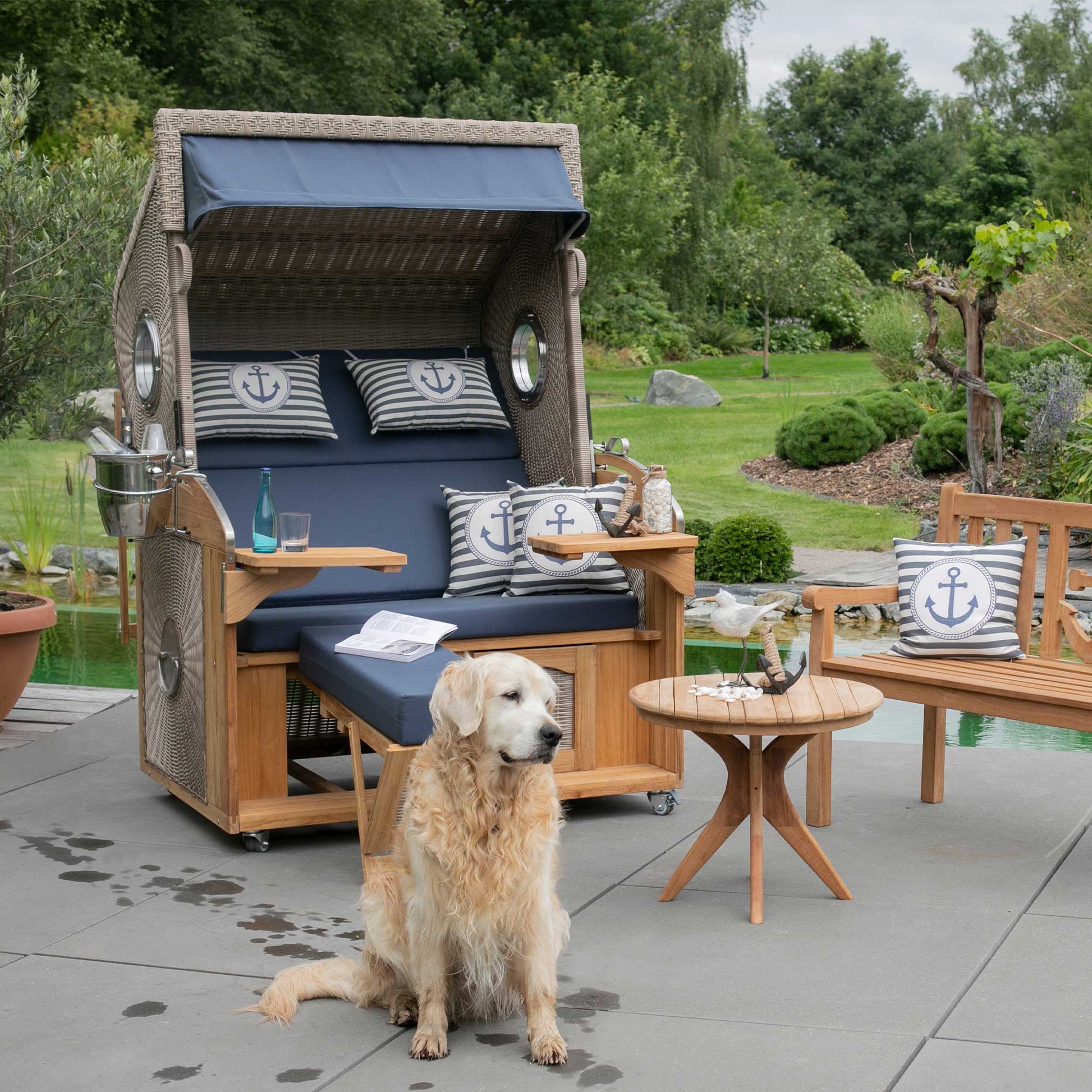 Strandkorb deVries Sailor PURE Teak XL PE white kubu Dessin 198 im Garten mit Hund und maritimen Kissen vor Teichanlage