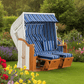 Strandkorb SunnySmart Rustikal 250 XL Plus in weiss mit blau weissen Streifenpolstern im blühenden Garten auf Rasenfläche