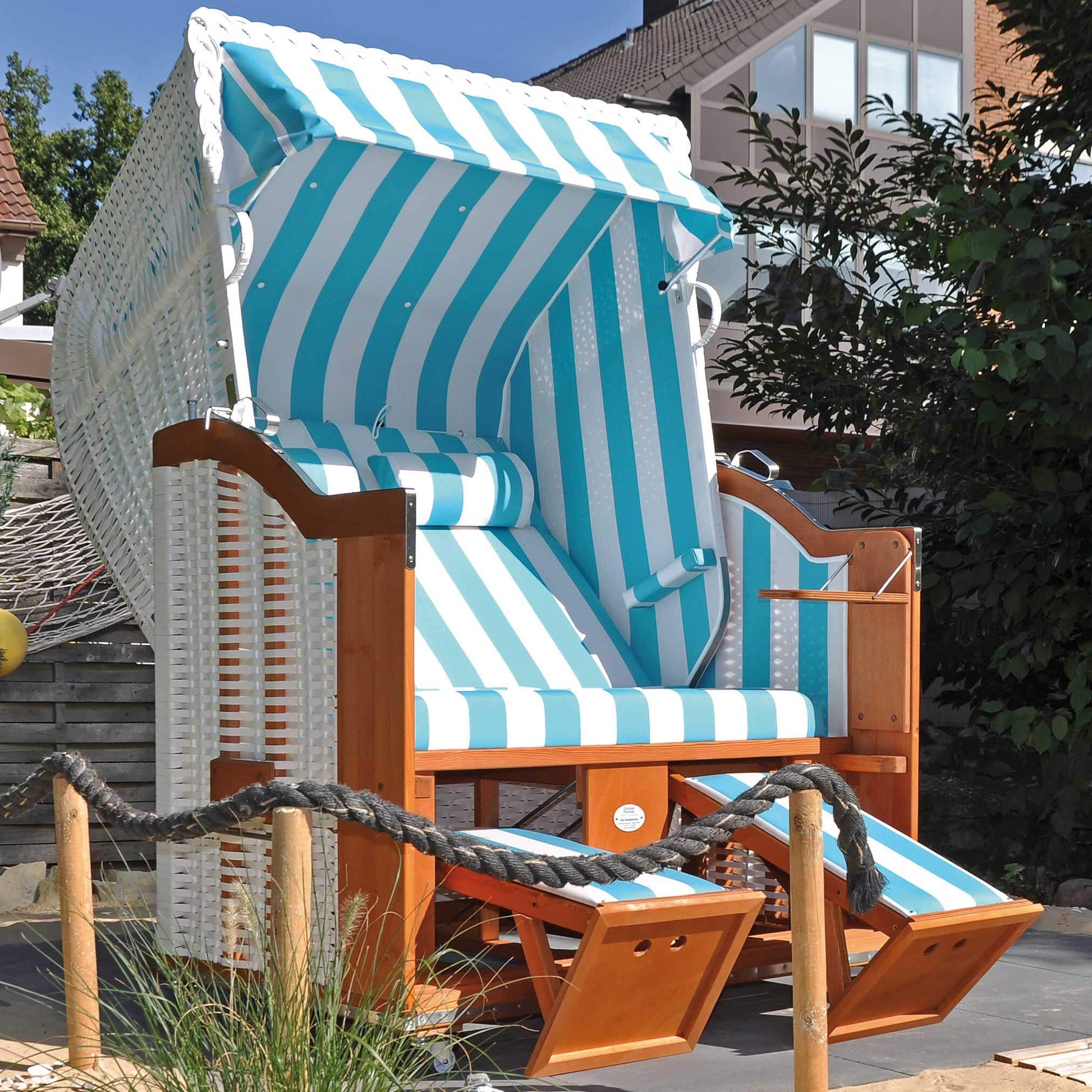 Strandkorb Sonnenpartner Modell Classic in türkis ocean mit Holzgestell und gestreiften Auflagen.